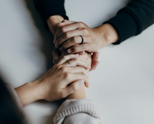 Two people holding hands across a table — couples entering residential rehab together