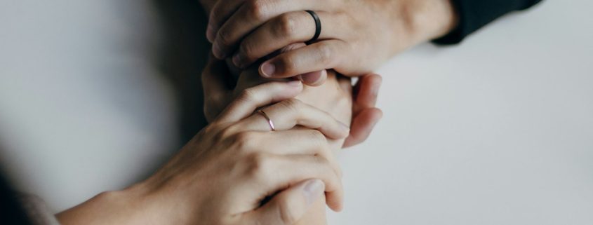 Two people holding hands across a table — couples entering residential rehab together