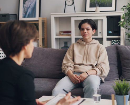 A clinician sitting with a client on a couch during a family-focused therapy session