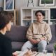 A clinician sitting with a client on a couch during a family-focused therapy session
