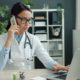 A physician working at a desk with laptop and phone — choosing a residential rehab program